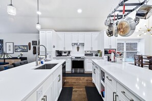 A modern kitchen with white cabinetry, stainless steel appliances, and a central island.