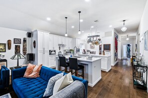 A modern kitchen with white cabinets, a central island, and pendant lighting.