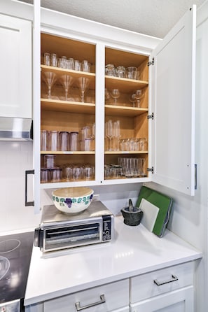 A kitchen with white cabinets, a bowl on the counter, a toaster, and a green tray. - Walcoff - A Birdy Vacation Rental (Schertz)