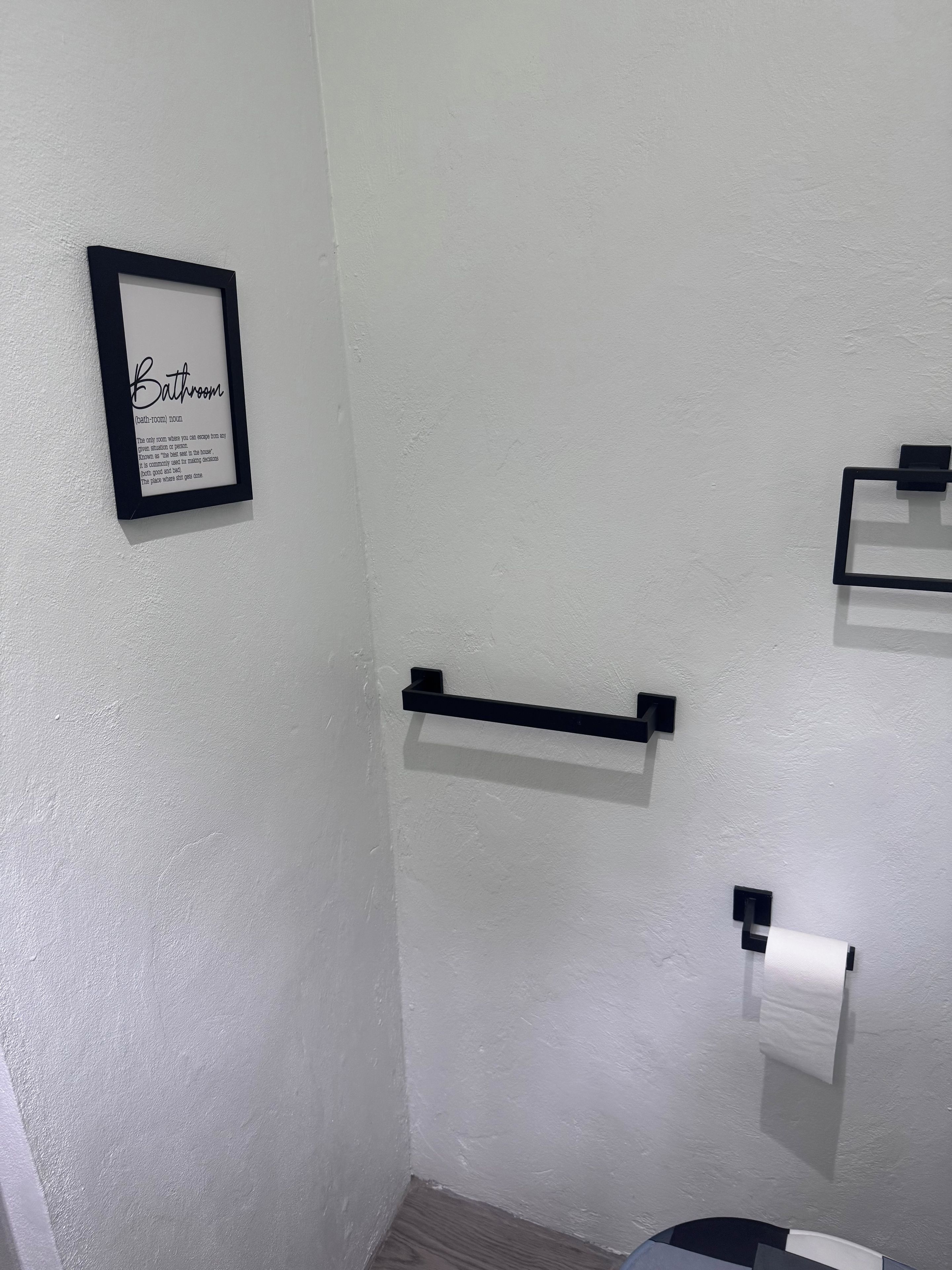 Une salle de bain avec un panneau encadré, un porte-serviettes et un support à papier toilette.