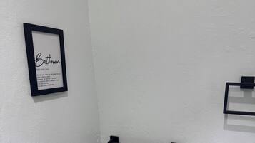 Une salle de bain avec un panneau encadré, un porte-serviettes et un support à papier toilette.