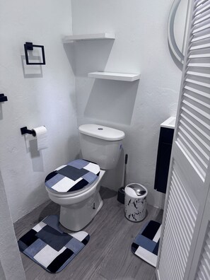 Pieni kylpyhuone, jossa on wc, bidee, wc-paperiteline ja pieni roskakori.