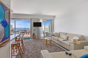 A modern living room with a sofa, a coffee table, and a TV. There is a balcony with a view of the sea. - Penthouse Garavan, Menton, France (Menton)