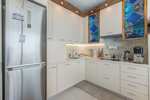 A modern kitchen with stainless steel appliances, white cabinetry, and a built-in stove. - Penthouse Garavan, Menton, France (Menton)