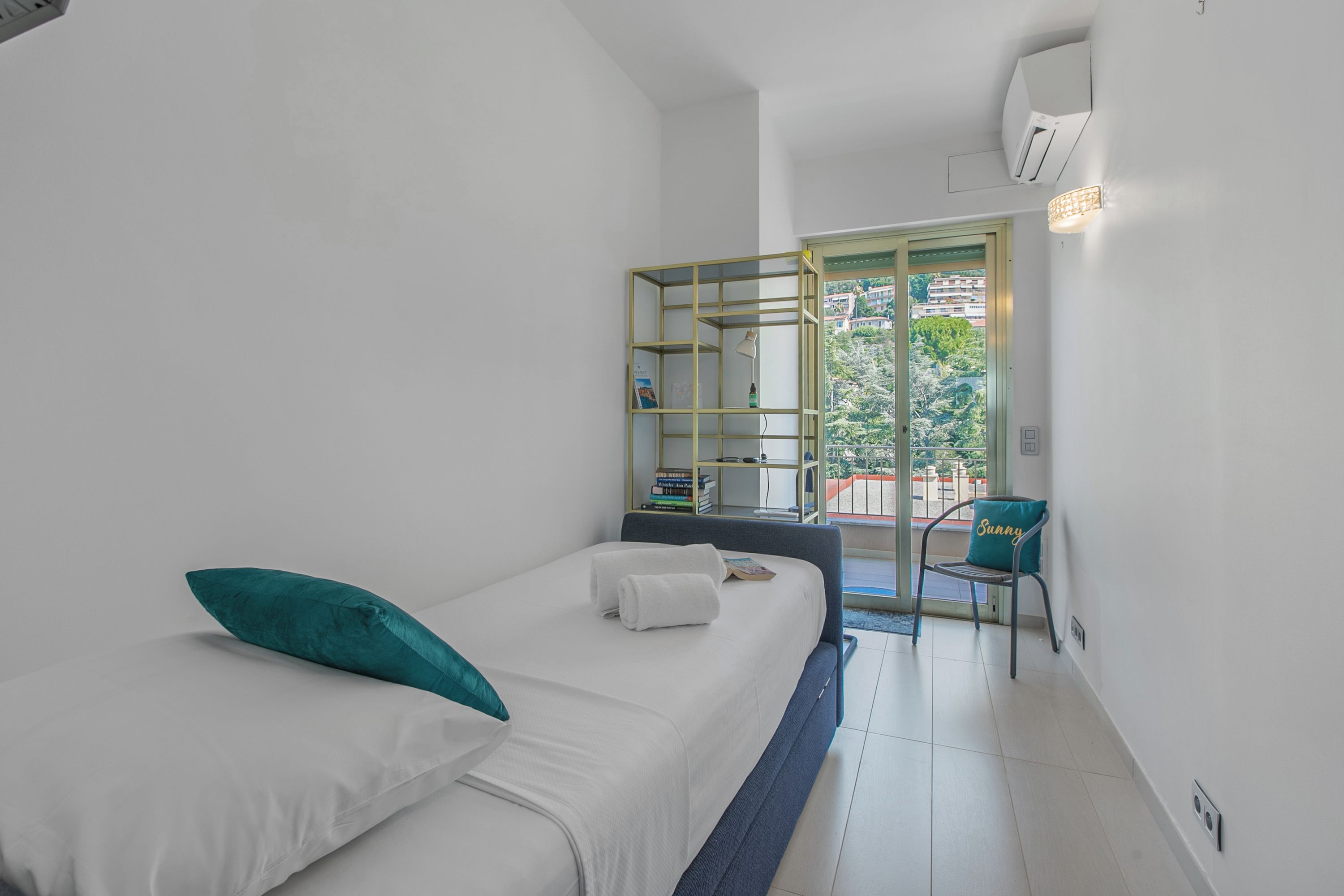 Una habitación pequeña y moderna con una cama, una silla y una estantería.