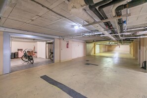 A spacious underground parking area with concrete floors and walls, a fire extinguisher mounted on the wall, and a bicycle parked in the corner. - Penthouse Garavan, Menton, France (Menton)