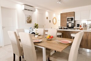 A modern kitchen with a wooden island, white cabinetry, and a dining area with a table set for four. - Comfort & Modern Sea-View 3 bdr Apart, Saint Paul's Bay, Malta (Saint Paul's Bay)