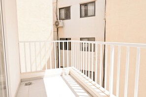 A narrow balcony with a white railing, a tiled floor, and a building with multiple windows in the background. - Comfort & Modern Sea-View 3 bdr Apart, Saint Paul's Bay, Malta (Saint Paul's Bay)