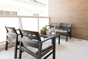 A balcony with a table and four chairs, a bottle of champagne, and a small plant. - Comfort & Modern Sea-View 3 bdr Apart, Saint Paul's Bay, Malta (Saint Paul's Bay)