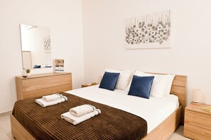 Habitación de hotel con una cama grande, un tocador de madera, un espejo y una obra de arte en la pared.