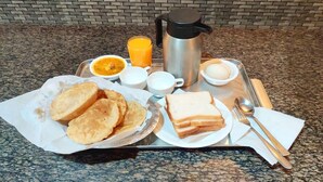 A breakfast tray with toast, eggs, orange juice, and a coffee pot.