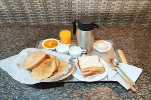 A breakfast tray with toast, eggs, orange juice, and a coffee pot.