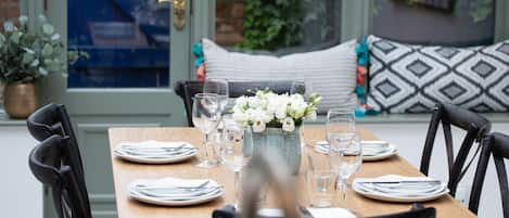A dining table set with plates, cutlery, and glasses, with a vase of flowers in the center.