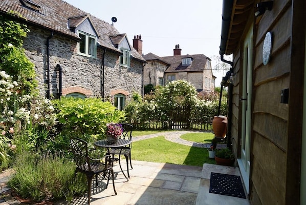 A stone house with a garden patio, a small table, and chairs.