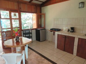 Cocina compacta con comedor, refrigerador, estufa a gas y cafetera.