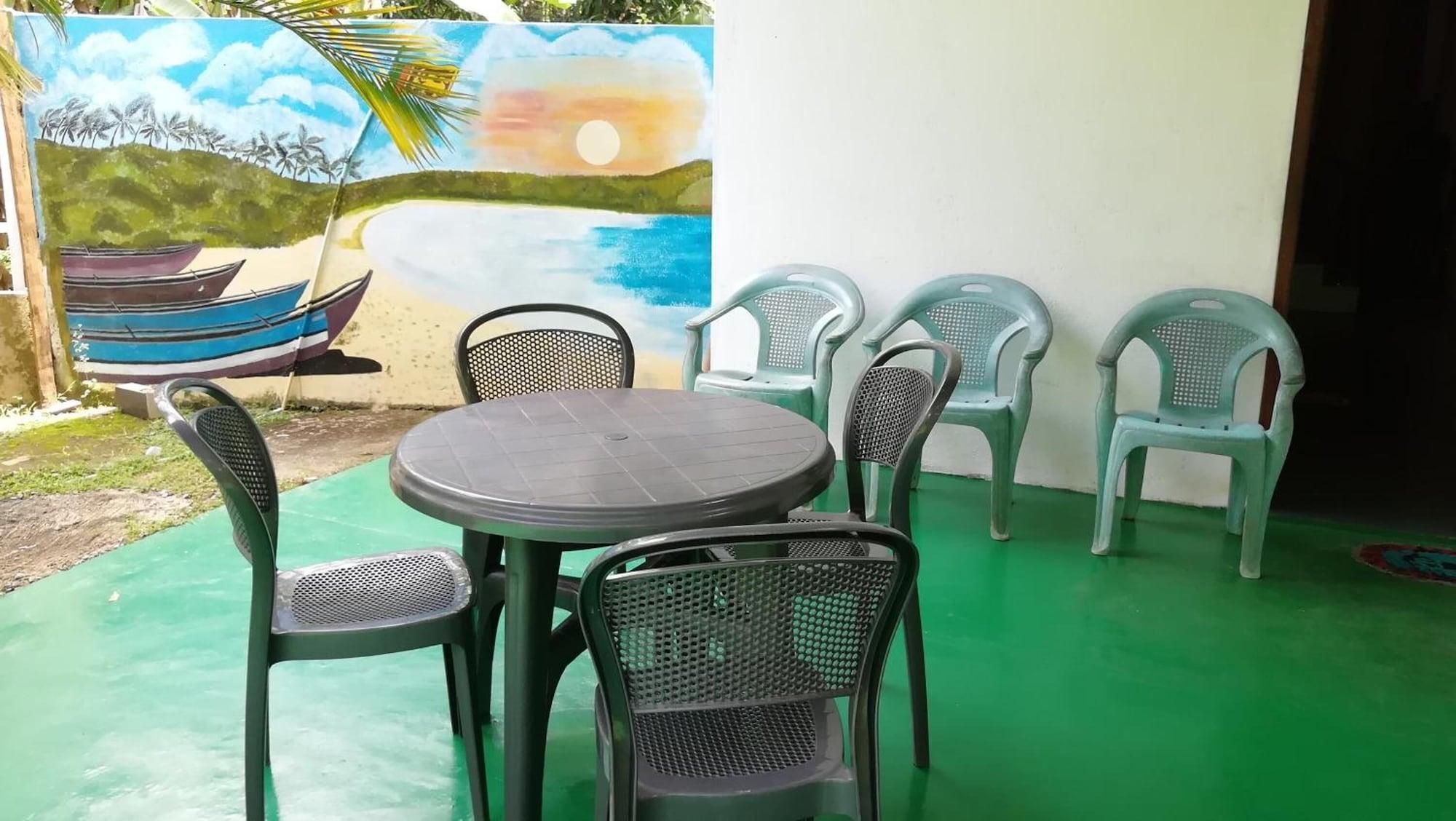 A dining area with a round table and chairs, a mural of a beach scene, and a green floor.