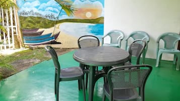 An outdoor seating area with a round table and chairs, a mural of a beach scene, and a small pool.