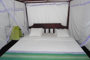 Una cama con dosel, dos almohadas y una colcha a rayas.