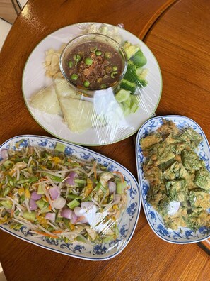 Una mesa con tres platos de comida, incluyendo una sopa de guisantes, una ensalada de verduras variadas y un plato con vegetales verdes.