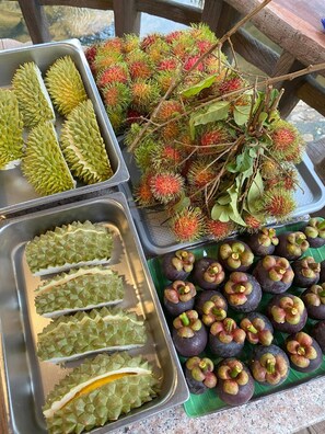Diversas frutas de durián y mangostán exhibidas en bandejas.