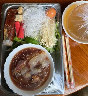 Bandeja de comida con diferentes alimentos, como fideos, verduras y un tazón de sopa.