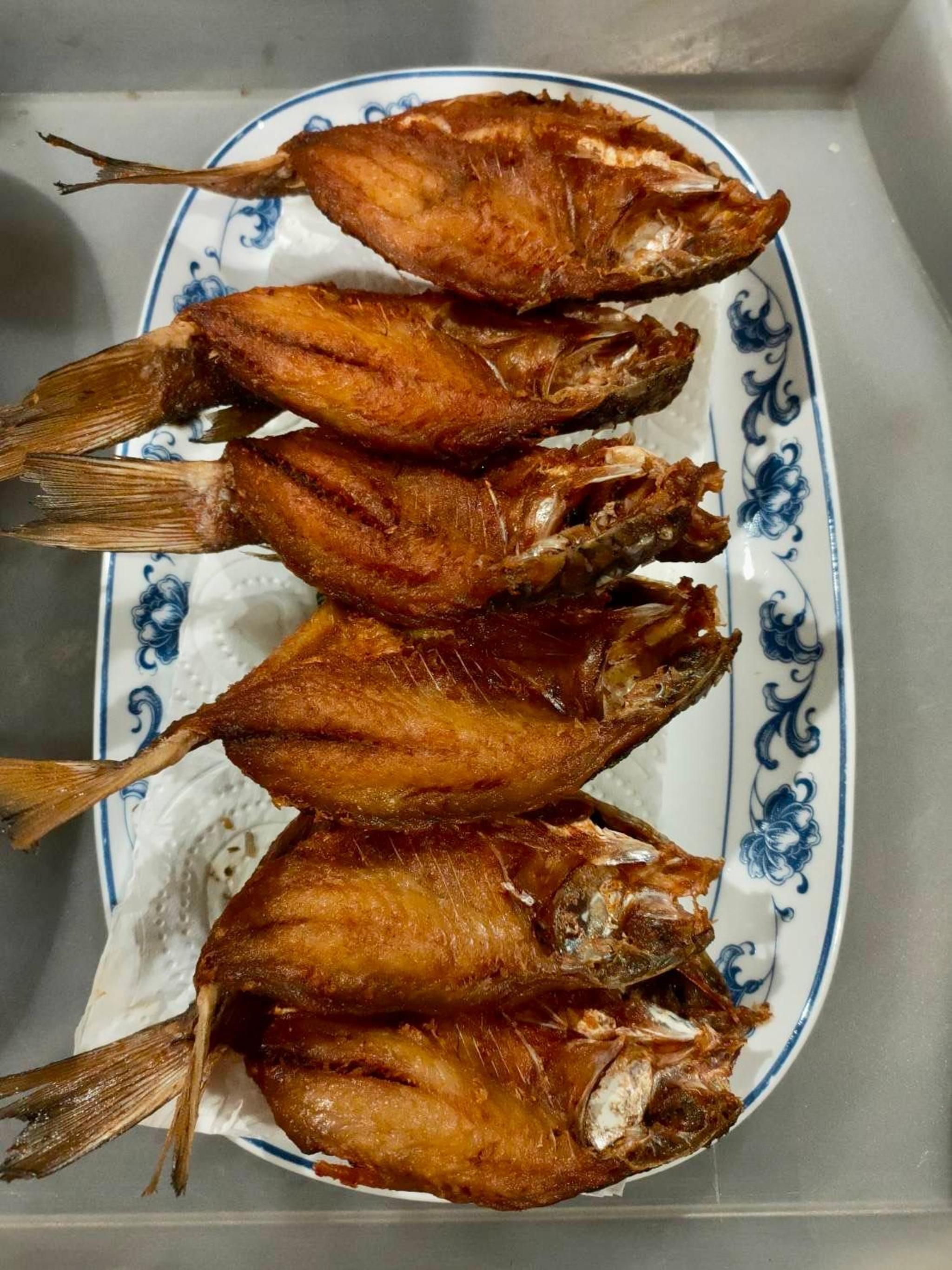 A plate of fried fish on a decorative plate.