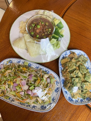 Una mesa con tres platos de comida, incluyendo una sopa de guisantes, una ensalada de verduras variadas y un plato con vegetales verdes.