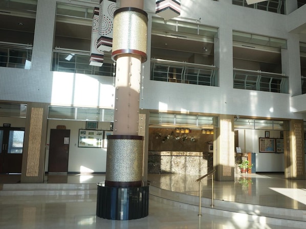 Un atri ample amb una columna central, finestres grans i una zona de recepció.