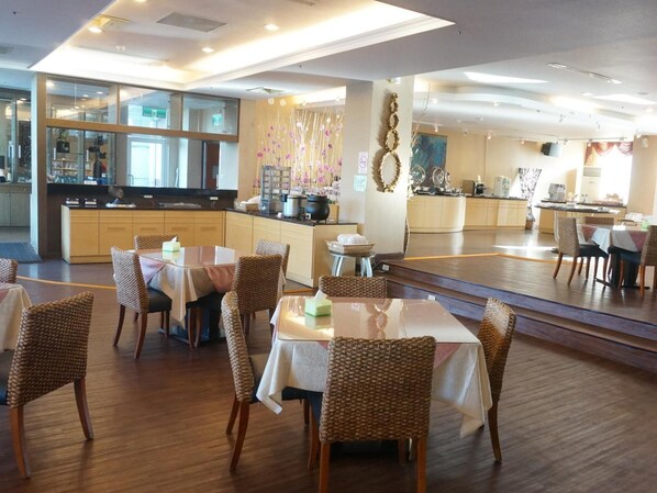 A restaurant with multiple dining tables and chairs, a kitchen area, and a bar. - East Coast Sea View Hotel (Chenggong)