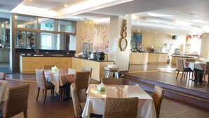 Ein Restaurant mit mehreren Tischen, Stühlen, einer Küche und einer Bar.