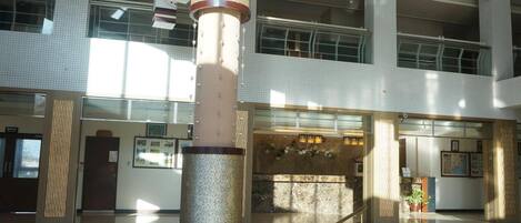 A spacious atrium with a central column, large windows, and a reception area.
