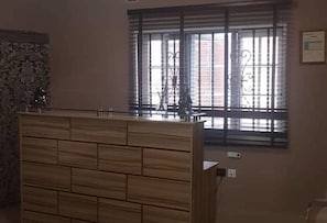 Una habitación con cabecera de madera, una ventana con barrotes de metal y un enchufe de pared.