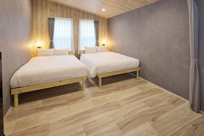 A room with two wooden beds, a wooden ceiling, and a grey wall.