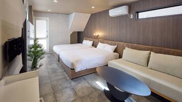 A modern hotel room with two beds, a sofa, a flat-screen TV, and an air conditioning unit.