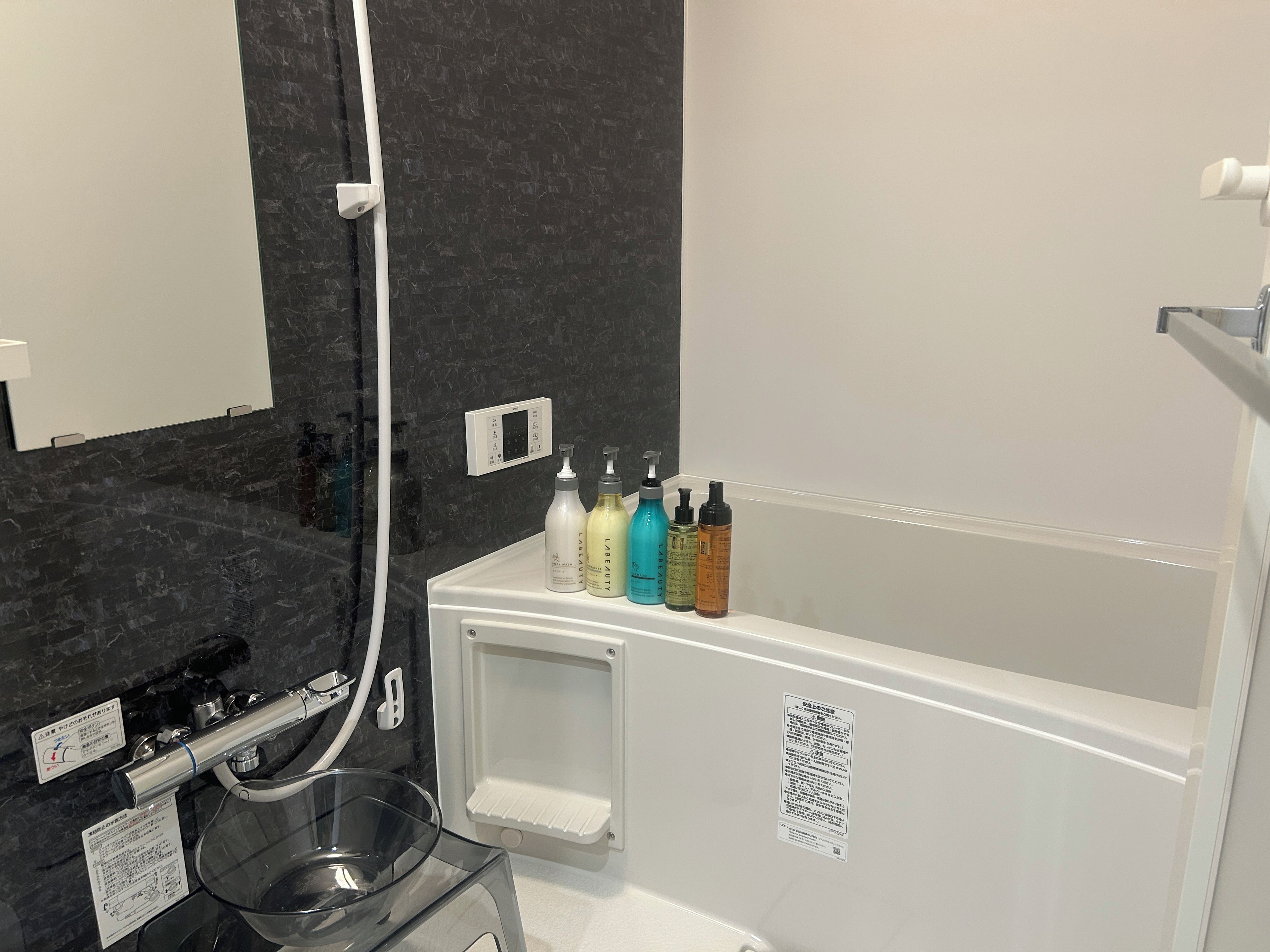 Une salle de bain moderne avec une baignoire, un lavabo en verre et un miroir. On trouve des articles de toilette sur le bord de la baignoire.