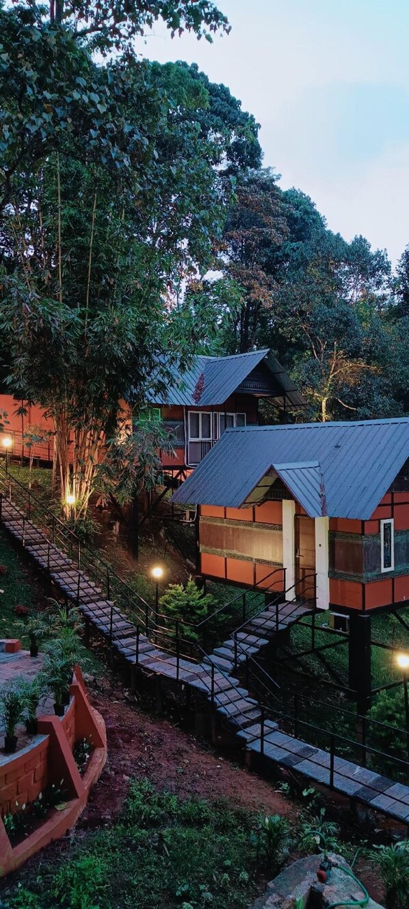 A treehouse-style building with a metal roof, surrounded by dense foliage. - Santhi Hill View Resort (Devikolam)