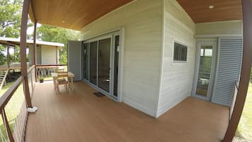 A covered outdoor area with a wooden deck, a table with chairs, and a sliding glass door leading to a covered patio.