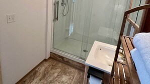 Pieni kylpyhuone, jossa on lasiseinällä varustettu suihku, pesuallas ja wc.