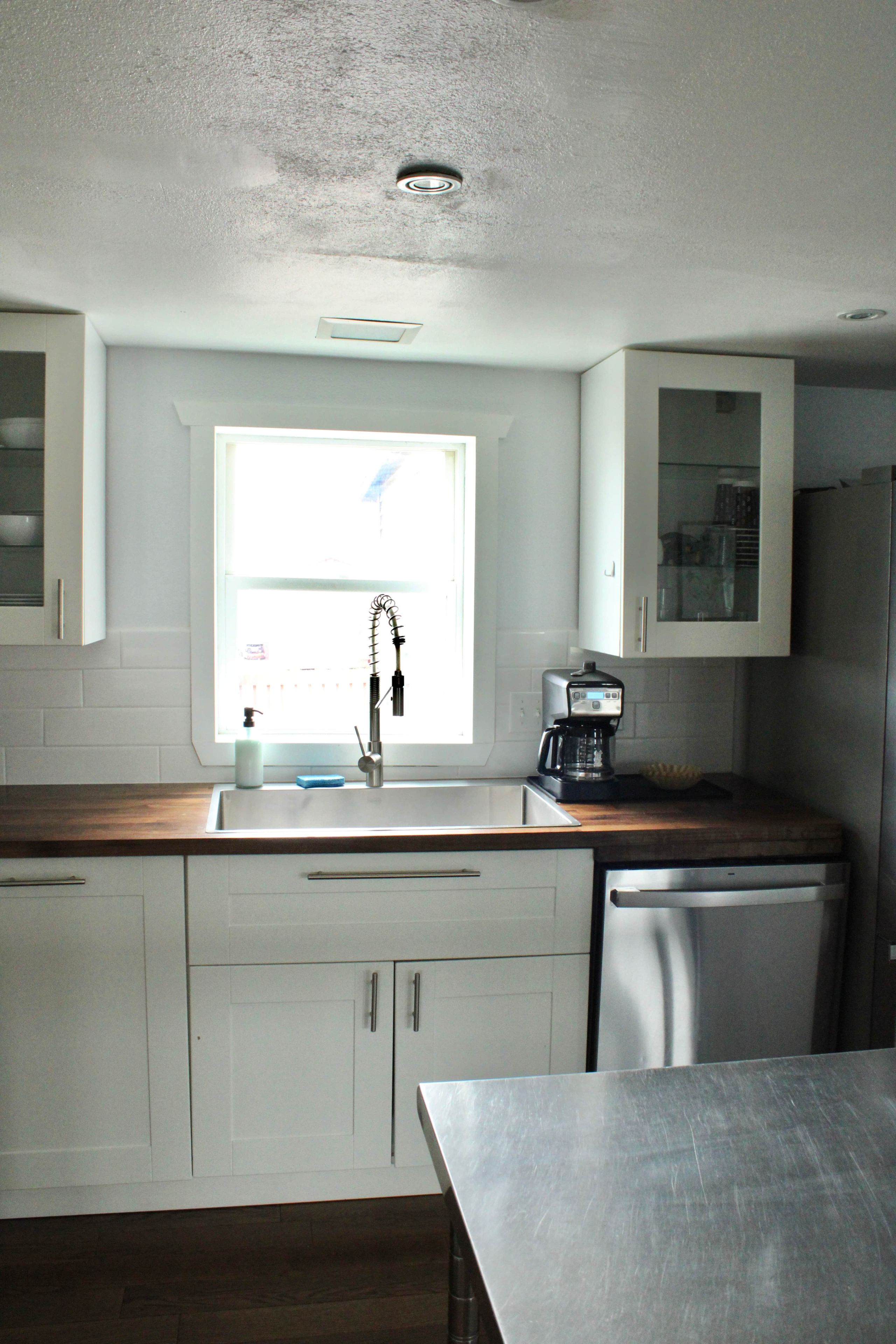 A kitchen with white cabinets, a stainless steel sink, a coffee maker, and a dishwasher.