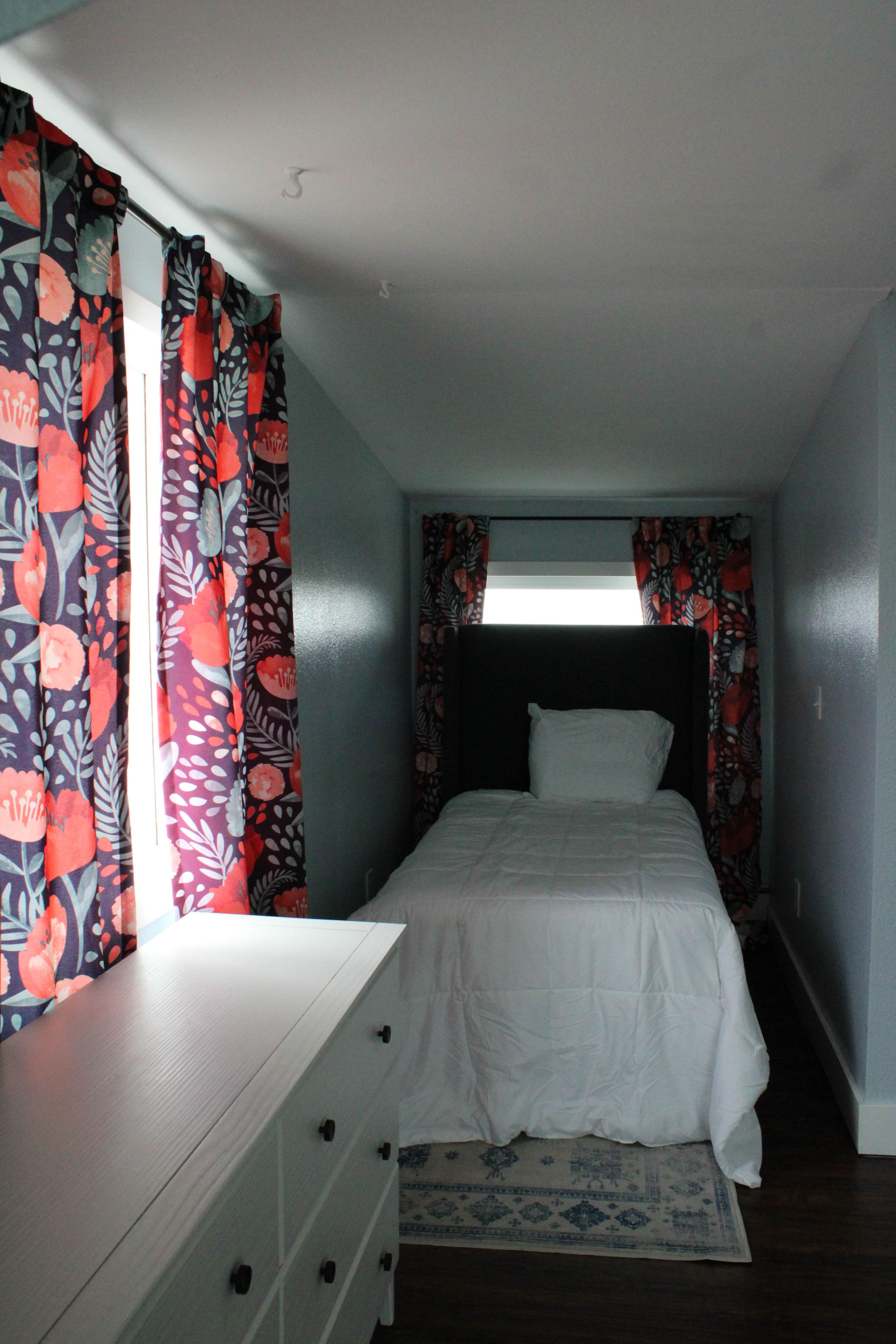 Un dormitorio con cama, cómoda y cortinas.