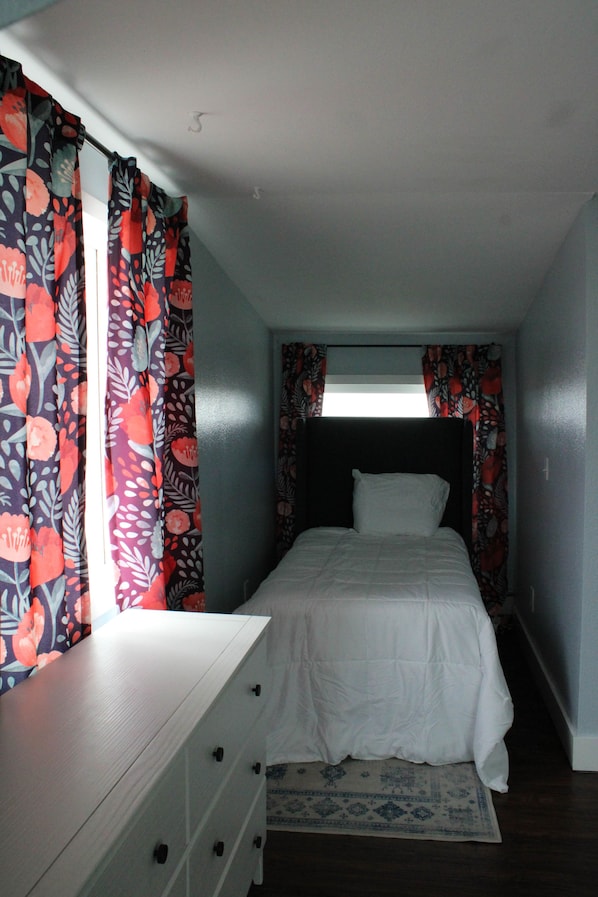 A bedroom with a bed, a dresser, and curtains.