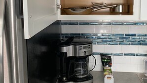Ett kök med ett kylskåp i rostfritt stål, en kaffebryggare och ett skåp med köksredskap.