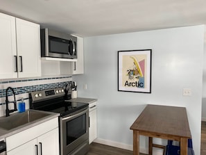 Eine moderne Küche mit Edelstahlgeräten, einer gefliesten Spritzschutzwand und einem gerahmten Bild an der Wand.