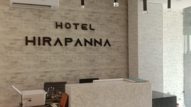 A hotel reception desk with a marble counter, a mounted air conditioner, and pendant lighting. - Hotel Hirapanna (Bareilly)