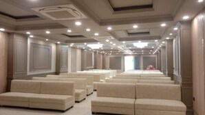 A hotel lobby with rows of beige sofas and a long corridor leading to a bright room. - Hotel Hirapanna (Bareilly)