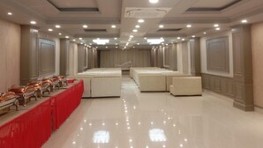 A spacious hotel room with a long dining table, multiple seating areas, and a modern ceiling design. - Hotel Hirapanna (Bareilly)