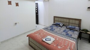 Ein Schlafzimmer mit einem Bett, einem Deckenventilator, einem Holzschrank und einem Nachttisch.