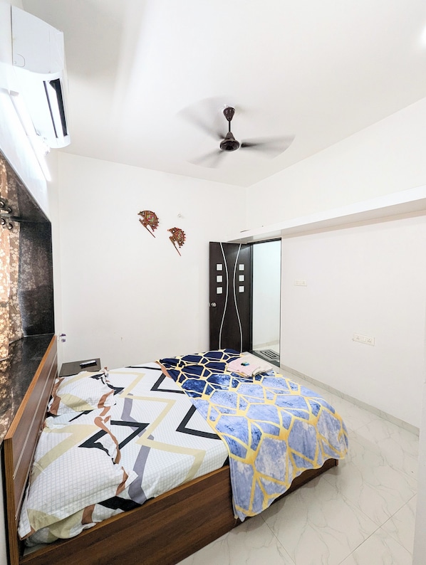 A bedroom with a bed, a ceiling fan, a wardrobe, and a door.