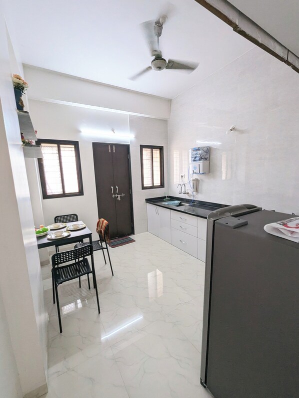 A modern kitchen with a refrigerator, stove, and ceiling fan.