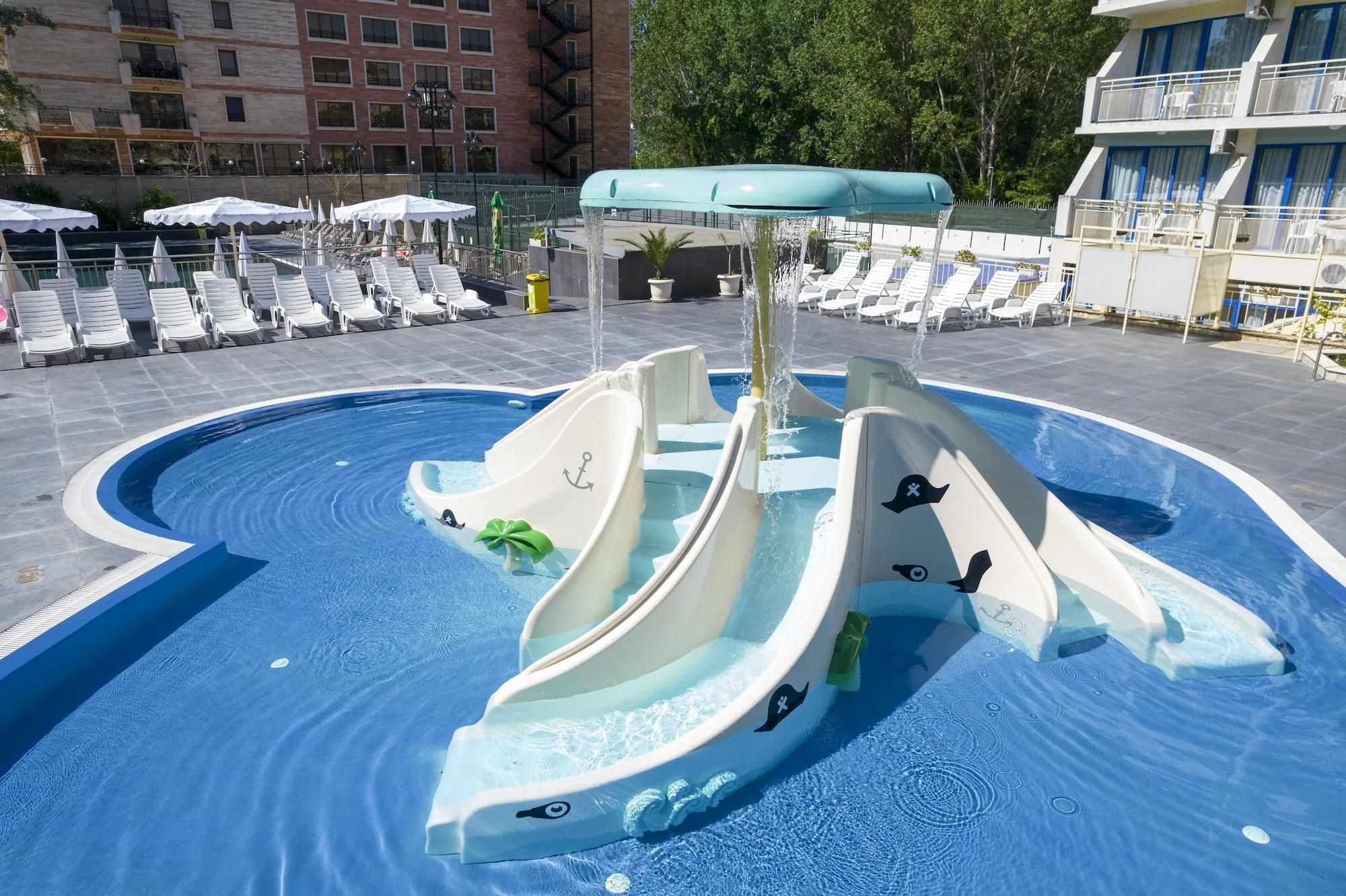 A pool with a water slide and lounge chairs.